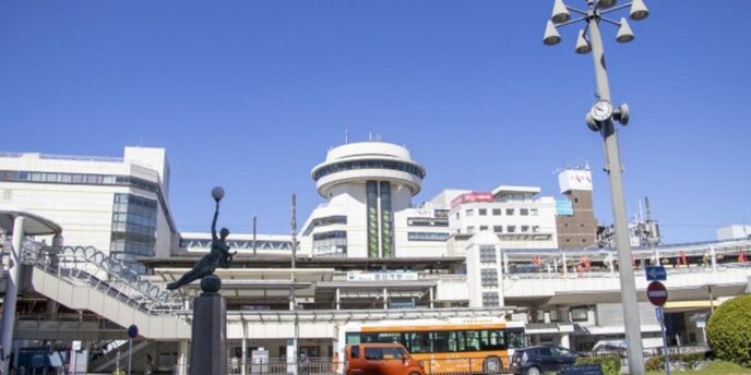 駅ビルと駅前ロータリー、バスや歩道橋が並ぶ駅周辺の街並み風景