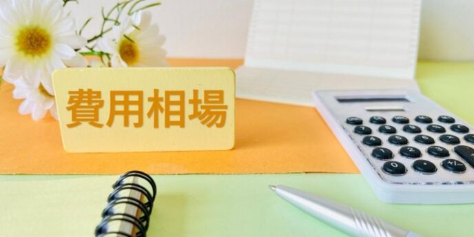 費用相談のイメージ。電卓、通帳、ペンなどが整った明るいデスクに「費用相談」の札。