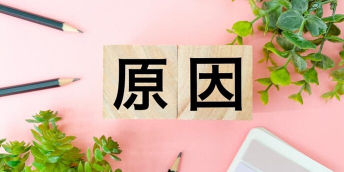ピンクの背景に「原因」と書かれた木製ブロックと観葉植物、鉛筆