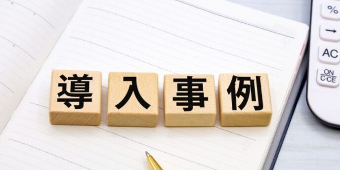 ノート上に並べられた木製ブロック「導入事例」の文字