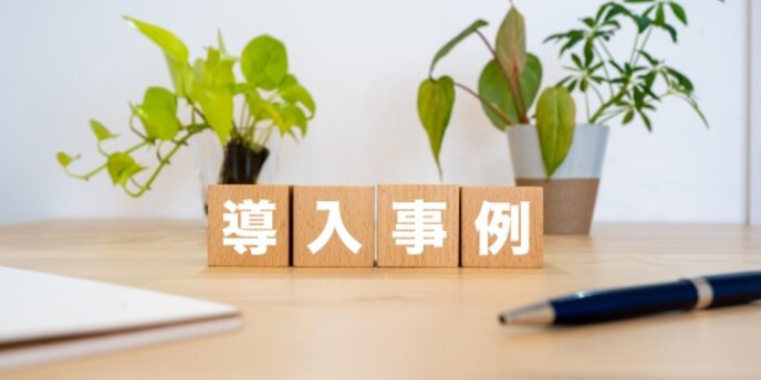 観葉植物のあるデスク上に置かれた「導入事例」と書かれた木製ブロック