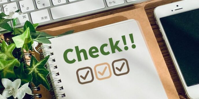 デスク上のノートに『Check!!』とチェックリスト、周囲にキーボードとスマートフォン