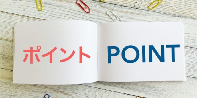 木製テーブルの上に開かれたノート、「ポイント」と「POINT」の文字と色とりどりのクリップ。