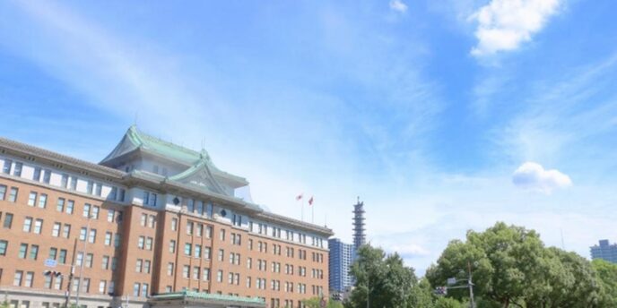 名古屋市役所本庁舎と晴れ渡る青空、歴史的建築と近代ビルが並ぶ都市風景。