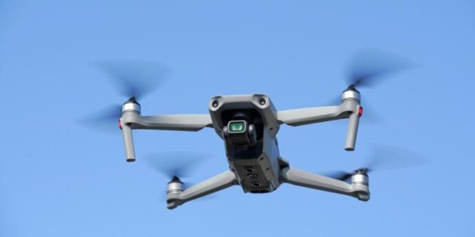青空の下で飛行する4枚羽の小型ドローンのクローズアップ