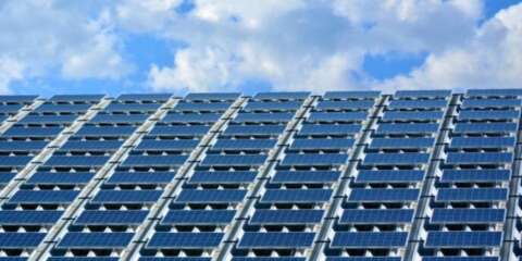 青空の下、建物の屋根全面に設置された多数の太陽光パネル