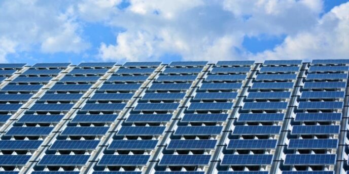 青空の下、建物の屋根全面に設置された多数の太陽光パネル