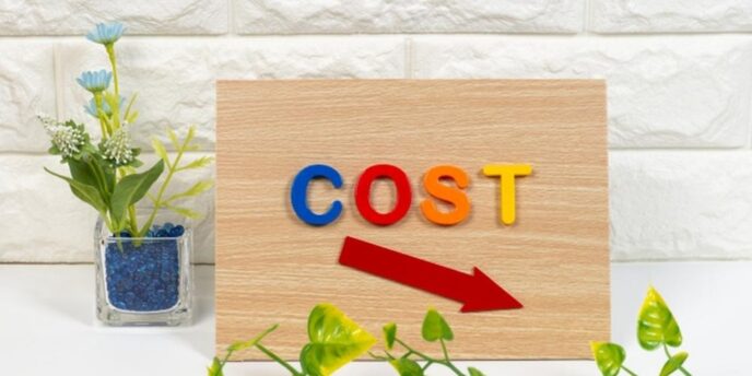 「COST」と書かれたボードと、コスト削減を示す赤い矢印。節約や低価格の印象。