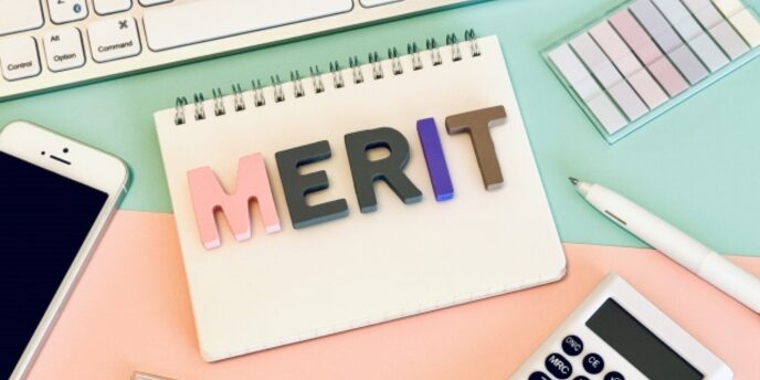 カラフルな文字で「MERIT」と描かれたノートとオフィス用品の構図
