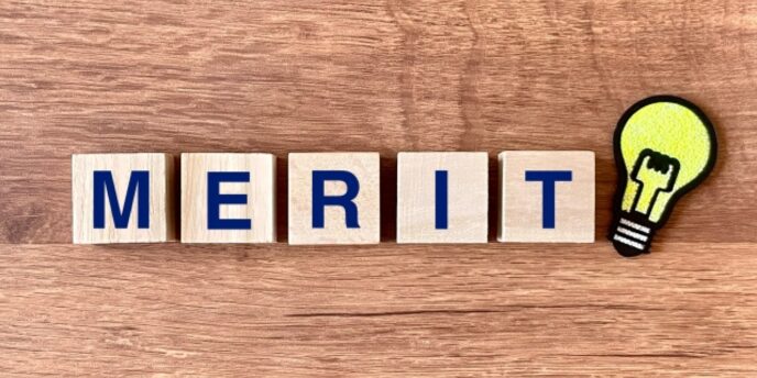 木のテーブルの上に「MERIT」と書かれたブロックと電球のイラストが並ぶ画像。