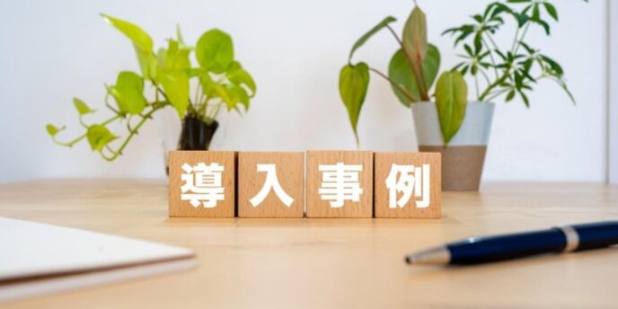 木製ブロックに「導入事例」と書かれた文字と観葉植物が並ぶ机上の写真