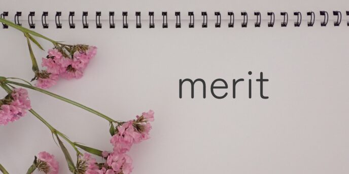 ノートに綴られた「merit」の文字とピンクの花、ペンのある構図