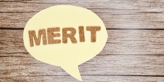 木目背景に貼られた『MERIT』の文字。利点やメリットを視覚的に表現したイメージ