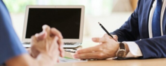 スーツを着た営業担当者が机越しに相談している様子
