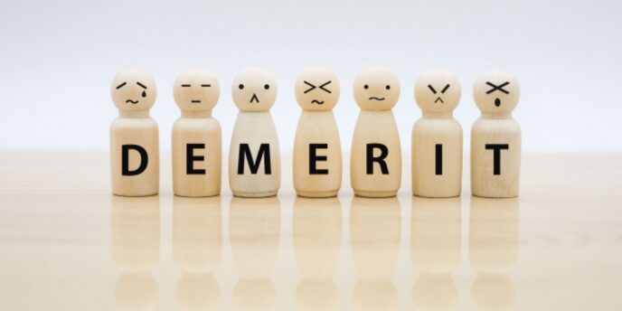 表情が描かれた木製人形が並び、「DEMERIT」と書かれている画像。
