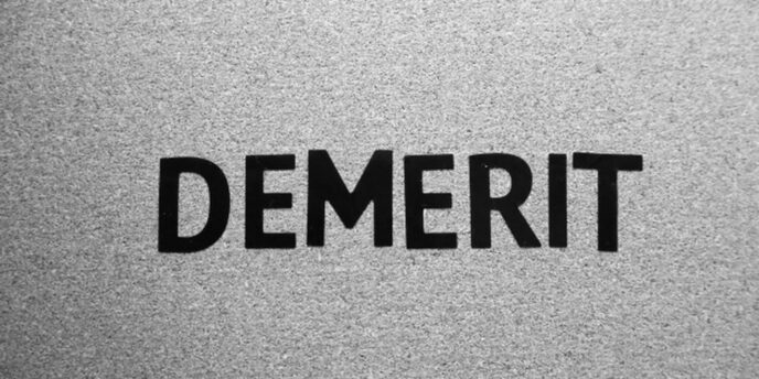 灰色の紙に黒字で「DEMERIT」と書かれたシンプルなモノクロ背景のイメージ