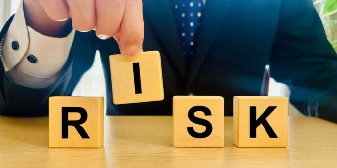 RISK画像:「スーツ姿の人物が『RISK』の文字が書かれた木製ブロックを並べているイメージ