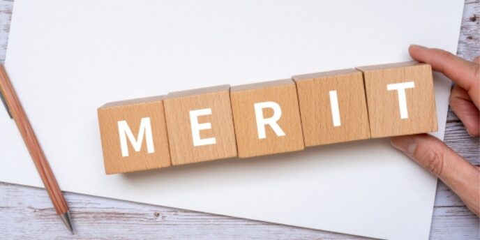 白紙の上に並べられた「MERIT」ブロックと手のイメージ