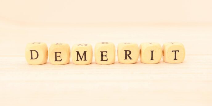 明るい木目背景に「DEMERIT」と並んだキューブ型の文字ブロック