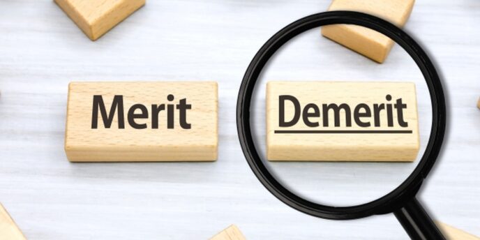 『Merit』と『Demerit』が書かれた木製ブロック、虫眼鏡がデメリットを強調