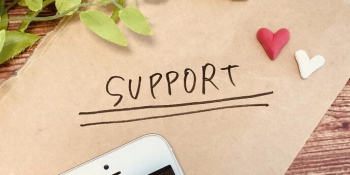 封筒の上に「SUPPORT」と書かれた文字とスマートフォン、小さなハート、観葉植物の装飾。