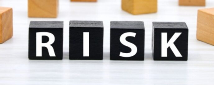 黒いブロックに「RISK」の文字が並び、周囲には茶色の木のキューブが置かれたイメージ。
