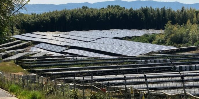フェンスで囲まれた太陽光パネルが複数並ぶ発電所の様子
