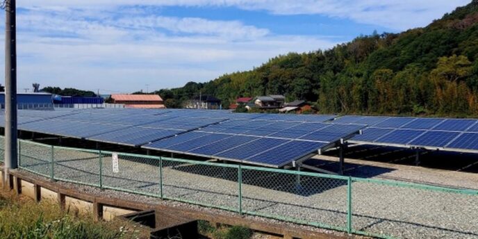 広大な敷地に設置された太陽光発電パネルと、奥に広がる田舎風景